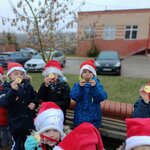 Dzieci z grupy Motylki ubrane w kurtki i świąteczne czapki mikołajowe prezentują zdobyte m.jpg