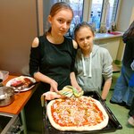 Dwie uczennice prezentują pizzę tuż przed umieszczeniem jej w piekarniku.jpg