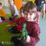 Chłopiec z grupy żabki trzyma w ręku zielonego dinozaura zabawkę...jpg