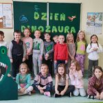 Dzieci z grupy Biedronek pozują do zdjecia na tle tablicy z napisem Dzień dinozaura...jpg