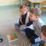 Grupka dzieci z grupy Misie siedzi na dywanie i układa puzzle z wizerunkiem dinozaura...jpg