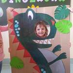 Dziewczynka z grupy Misie pozuje do zdjęcia w fotobudce z wizerunkiem dinozaura...jpg