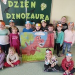 Dzieci z grupy motylki stoją na tle dekoracji z okazji dnia dinozaura..jpg
