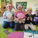 Dzieci z grupy motylki siedzą na dywanie i pozują do zdjęcia z dinozaurami zrobionymi z balonów i kolorowych papierów..jpg