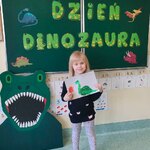 Dziewczynka z grupy Biedronek prezentuje swoją pracę plastyczną pt. Dinozaur..jpg