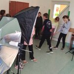 Grupa uczniów w sali rozmawia ze sobą_ obok parasole fotograficzne i tła do zdjęć.jpg