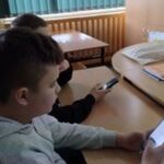 Zdjęcie 5-przedstawia dwóch chłopców z telefonami patrzącymi w ekran i klikającymi na klawiaturze.