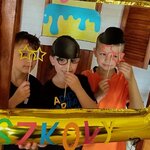 Grupa uczniów wraz z wychowawczynią pozują w złotej fotobudce.