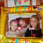 Grupa uczniów wraz z wychowawczynią pozują w złotej fotobudce.