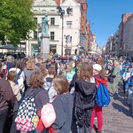 Grupa dzieci na rynku w Toruniu podczas zwiedzania Starego Miasta -  w tle pomnik Mikołaja Kopernika.