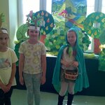 Zielony Kapturek i dzieci przebrane za drzewka na tle dekoracji teatralnej.jpg