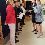 Pani dyrektor wręcza podziękowania nauczycielom_ w tle widać uczennice i uczniów należącyc.jpg