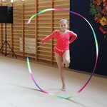 Gimnastyczka prezentuje na sali gimnastycznej układ choreograficzny z szarfą_ w tle dekora.jpg