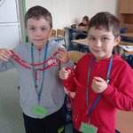 Dwóch chłopców_ stojących obok siebie_ prezentuje trzymane w uniesionych rękach_ wykonane .jpg