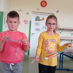 Dwoje dzieci_ chłopiec i dziewczynka_ pokazują w uniesionych rękach wykonane własnorecznie.jpg