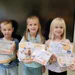 Dzieci z grupy Biedronek pozują do zdjęcia trzymając nagrody za przyniesienie karmy na rzecz schroniska dla zwierząt.jpg