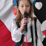 Dziewczynka w wianku z grupy Biedronki stoi z mikrofonem.jpg