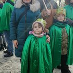Na zdjęciu widać dwie osoby dorosłe i dwójkę dzieci w zielonych pelerynach i w koronach.