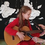 dziewczynka grająca na gitarze i śpiewająca do mikrofonu.jpg.jpg